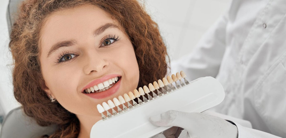 Woman choosing porcelain veneer tooth shades.
